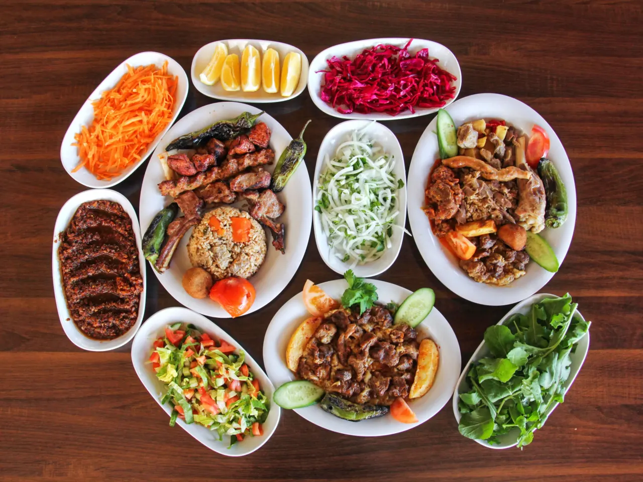 Koyu ahşap masada kebaplar, lahmacun ve meze tabakları