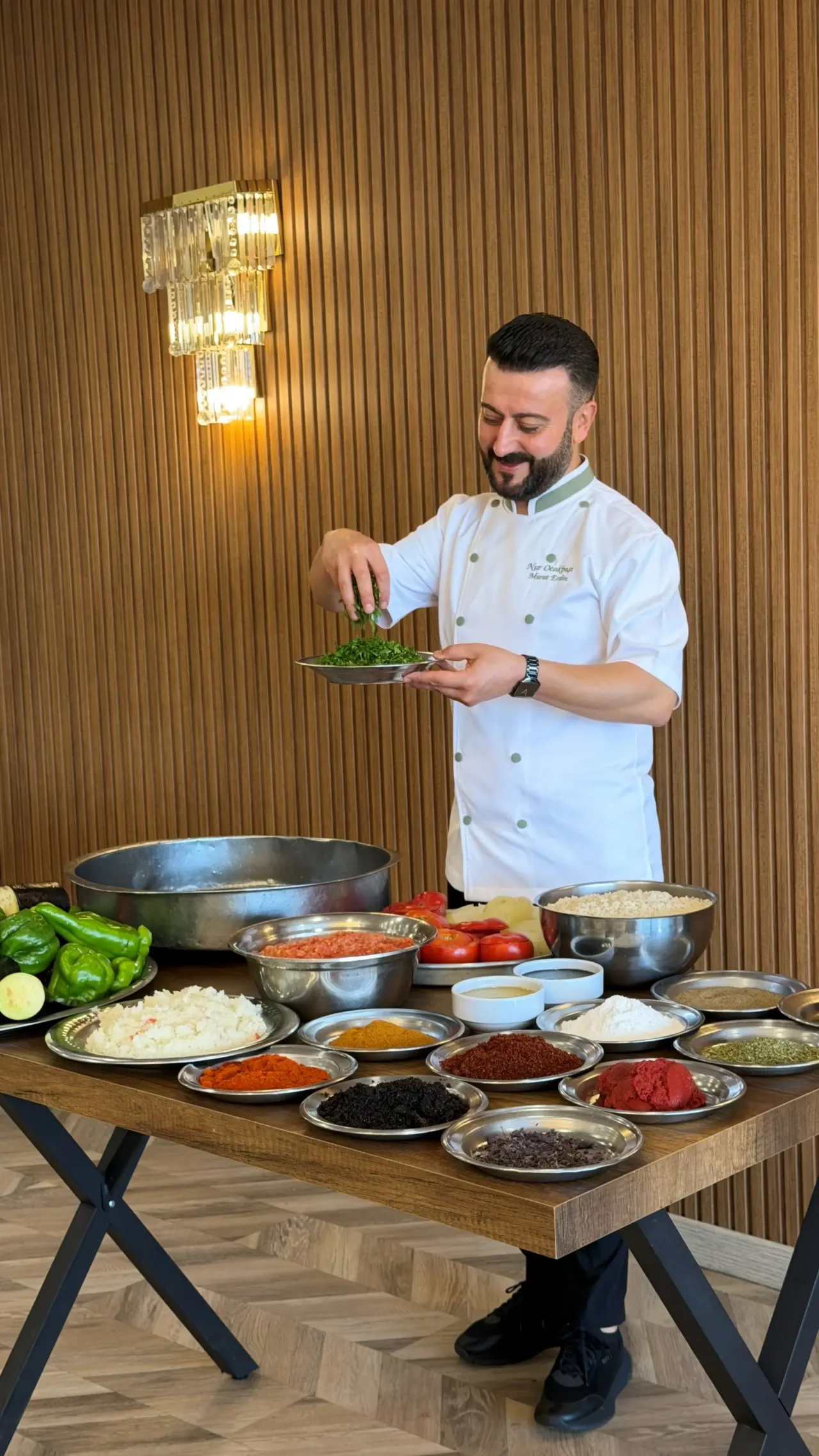 A cook garnishing a serving plate in front of bowls of spices and vegetables