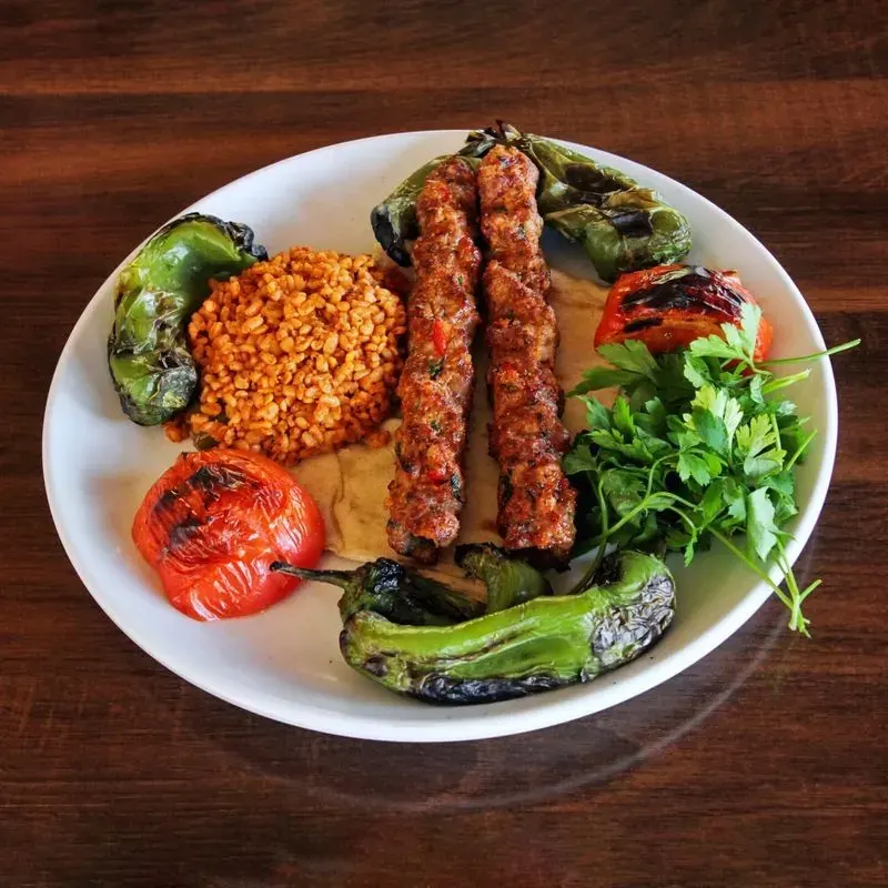 Közlenmiş biber ve domatesle servis edilen Adana kebap