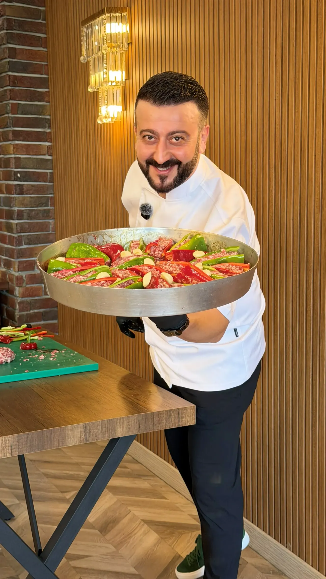 Beyaz ceketli aşçı, biber ve domatesle hazırlanmış büyük bir kebap tepsisini taşıyor